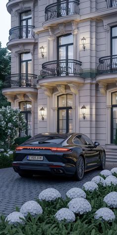 a black sports car parked in front of a large building with balconies on it