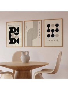 three black and white art prints hanging on the wall above a table with two chairs