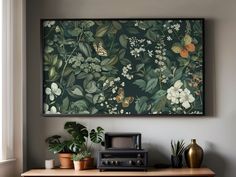 a painting hanging on the wall above a table with potted plants and an old radio