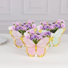 two butterfly shaped vases filled with purple flowers