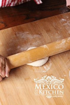 a person rolling dough on top of a wooden table