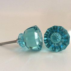 two blue glass knobs on a white surface