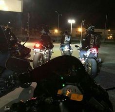 three motorcycles are parked in a parking lot at night with their lights on and there is no image to provide a caption for