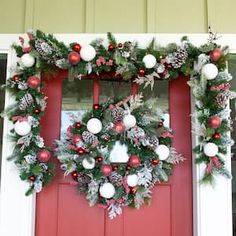 a red door decorated with christmas wreaths and ornaments