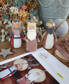 three wooden figurines sitting on top of a table next to an open book