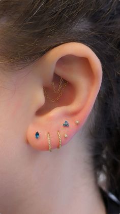 a close up of a person's ear with three different colored stones on it