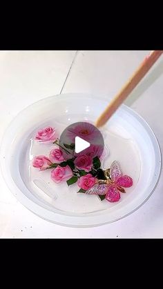 a white plate with pink flowers and a wooden stick in it, on a table