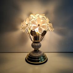 a lamp that is on top of a table with flowers in the center and light coming from it