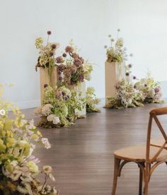 several vases filled with flowers on top of a wooden floor next to a chair