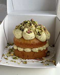 a cake in a box with pistachios on top and white frosting