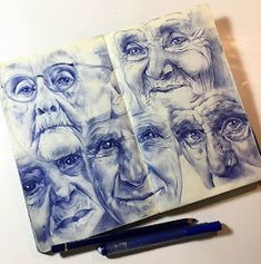 two notebooks with drawings of people's faces on them and a blue pen