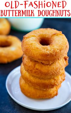 a stack of doughnuts sitting on top of a white plate next to a glass of milk