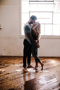 a man and woman dancing in an empty room with sunlight streaming through the window behind them