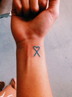 a person with a tattoo on their wrist holding up a blue heart and an x