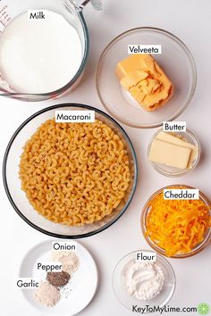 ingredients to make macaroni and cheese are shown in bowls on a white surface