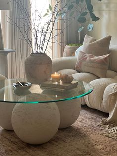 a living room filled with furniture and a glass top table in front of a window