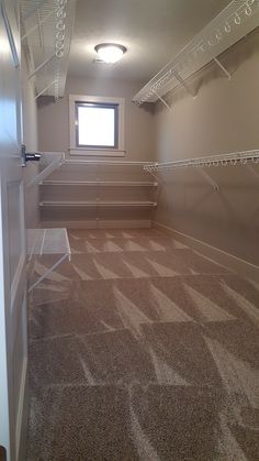 an empty room with some shelves and carpet on the floor in front of a window