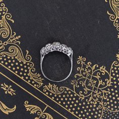 a diamond ring sitting on top of a black and gold table cloth with ornate designs