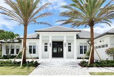 a white house with two palm trees in front of it and a walkway leading to the front door