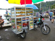 a motorcycle parked next to a display case with donuts and other foods on it