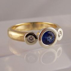 a close up of a ring with a blue stone and two white diamonds on it