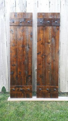 two wooden doors sitting next to each other on top of a grass covered field,