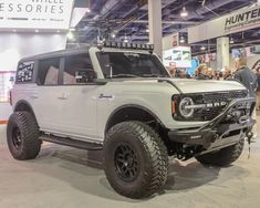 a large white truck on display at an auto show with people looking around the room