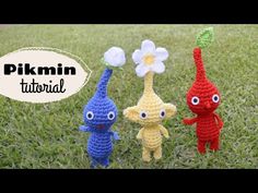 three crocheted toys are standing in the grass with flowers on their heads and eyes