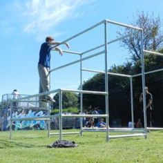 a man standing on top of a metal structure in the middle of a grass field