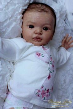 a baby laying on top of a white blanket