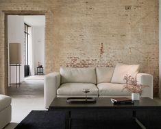 a living room with a white couch and black coffee table in front of a brick wall