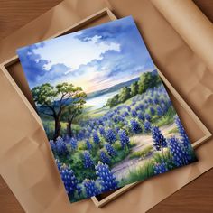 a painting of a bluebonnet field with trees and water in the background on a piece of cardboard