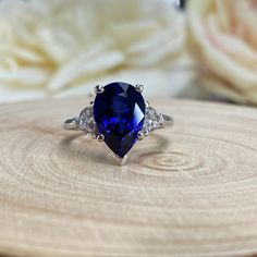 a tan and white ring with a blue stone surrounded by three diamonds on a piece of wood