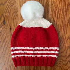 a red and white knitted hat with a pom - pom