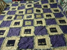 a purple and black quilted blanket on a table with wooden chairs in the background