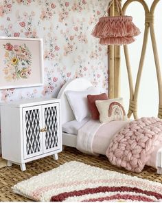 a bedroom with floral wallpaper and bedding in pink, white and red colors