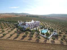 an aerial view of a large white house with a pool in the middle of it