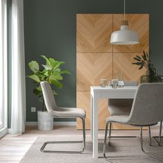 a dining room table with two chairs and a potted plant in the corner next to it