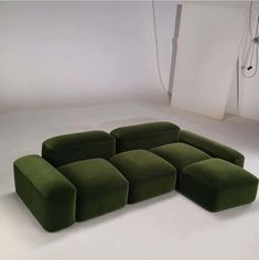 a large green couch sitting on top of a white floor next to a light fixture