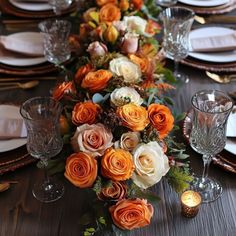 an elegant table setting with orange and white flowers on the centerpieces, candles and place settings