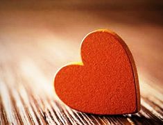 a red heart sitting on top of a wooden table