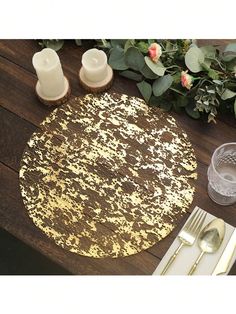 a placemat with gold paint on it next to some silverware and candle holders