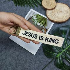 someone holding a keychain that says jesus is king