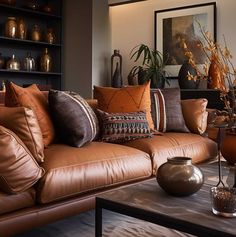 a living room filled with lots of brown couches next to a coffee table and vases