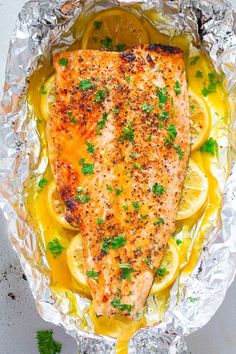 salmon with lemon and parsley on foil in a skillet, ready to be cooked