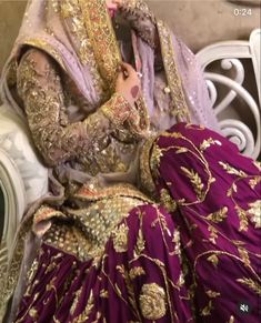 a woman sitting on top of a white chair wearing a purple dress and headpiece