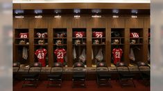 the locker room is filled with football jerseys and helmets on display in wooden cases, along with black chairs