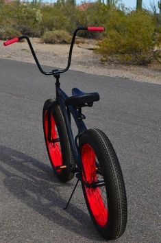 a black bike with red spokes on the road