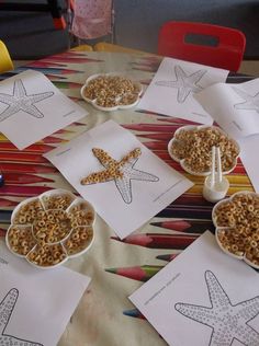 some little bowls filled with cereal and starfish on top of a colorful table cloth