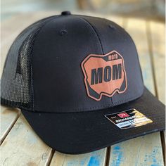 This one goes out to all of the Moto Moms out there. Represent your love for Moto on and off the track with our personalized custom leatherette patch hats! RICHARDSON 112 SNAPBACK INFORMATION: CLOSURE: Plastic Snapback strap SHAPE Mid-Pro FABRIC Cotton-Poly/Nylon Mesh VISOR Precurved SWEATBAND Cotton MATERIAL 60% Cotton, 40% Polyester CONSTRUCTION Woven/Knitted This hat features a 'Rust' colored leatherette patch which lends the perfect touch of character while maintaining refined style. Our pat Personalized Black Curved Bill Snapback Hat, Black Leather Trucker Hat For Outdoor, Black Trucker Hat With Leather Patch For Outdoor, Black Trucker Hat With Leather Patch, Customizable Black Custom Snapback Hat, Customizable Black Snapback Hat, Black Leather Trucker Hat, Black Leather Snapback Hat With Curved Bill, Custom Black Hat With Leather Patch